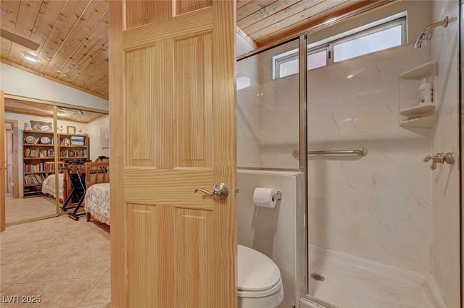 Ensuite bathroom featuring wooden ceiling, a marble finish shower, toilet, tile patterned flooring, and lofted ceiling | Image 56