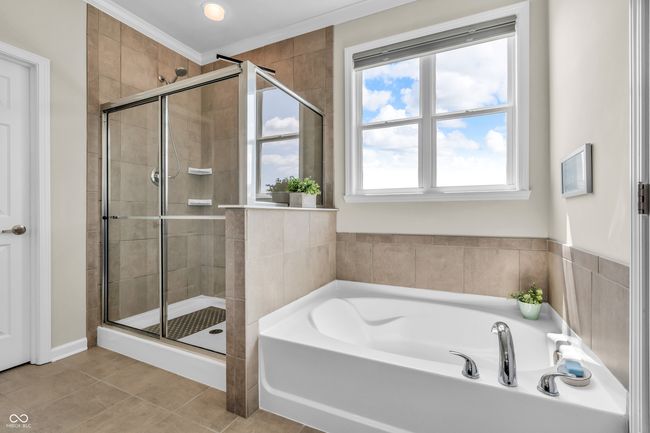 master bath with a tiled shower stall, tiled floors, ornamental molding and garden tub | Image 37