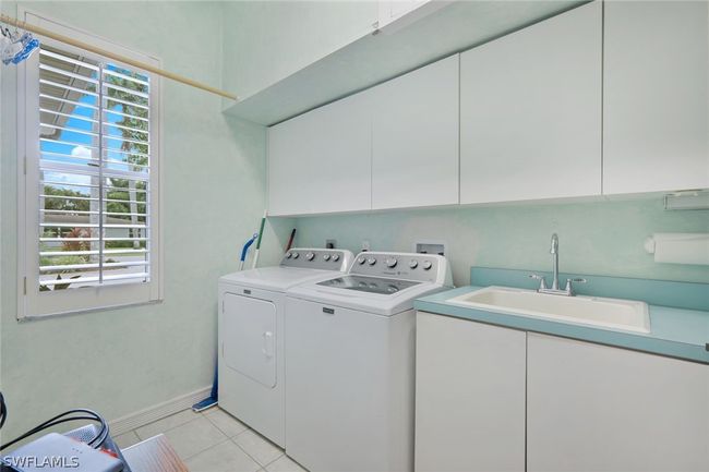 Laundry room featuring washer and clothes dryer, sink, cabinets, and light tile patterned floors | Image 37