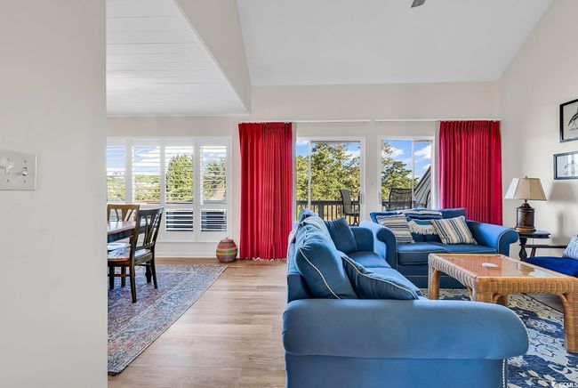 Living room with baseboards, vaulted ceiling, a wealth of natural light, and wood finished floors | Image 14