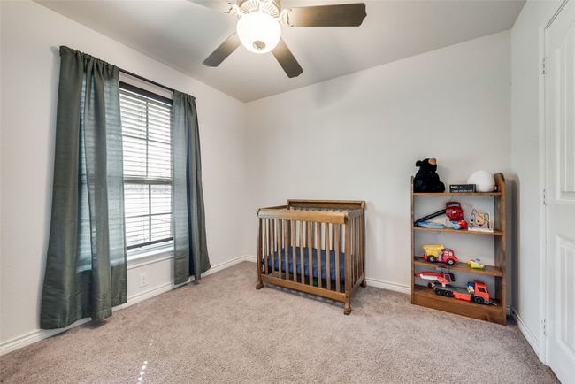 Bedroom with carpet flooring, ceiling fan, baseboards, and a nursery area | Image 19