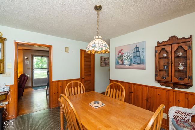 dining room with a wainscoted wall, wood walls, and a textured ceiling | Image 10