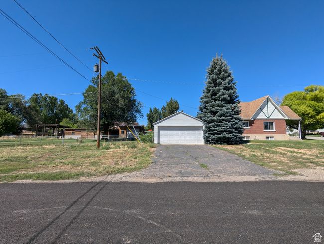 View of front of home with a detached garage, an outbuilding, and fence | Image 46