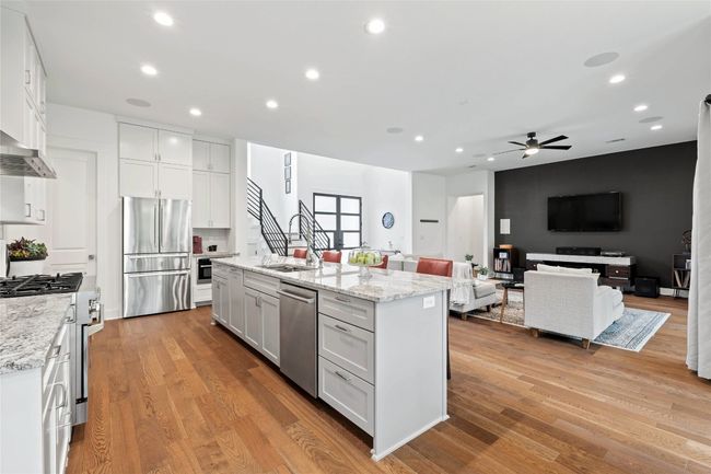 Kitchen featuring stainless steel appliances, a ceiling fan, white cabinetry, light wood-style flooring, and recessed lighting | Image 6
