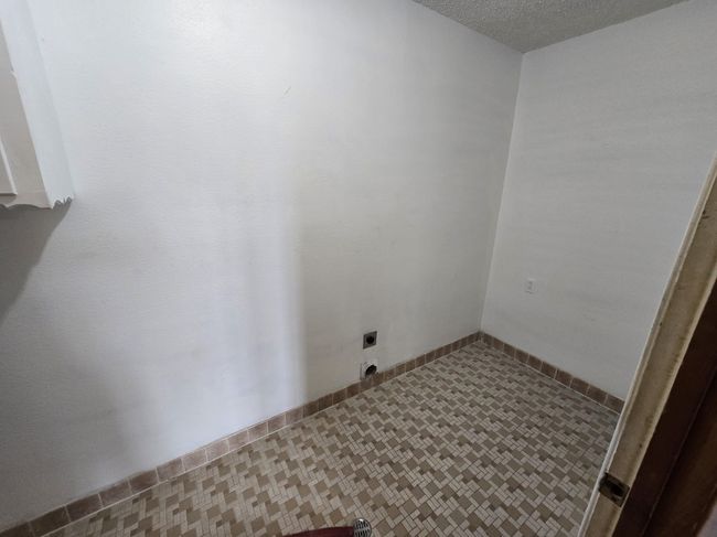 Washroom featuring hookup for an electric dryer, a textured ceiling, and tile patterned floors | Image 18
