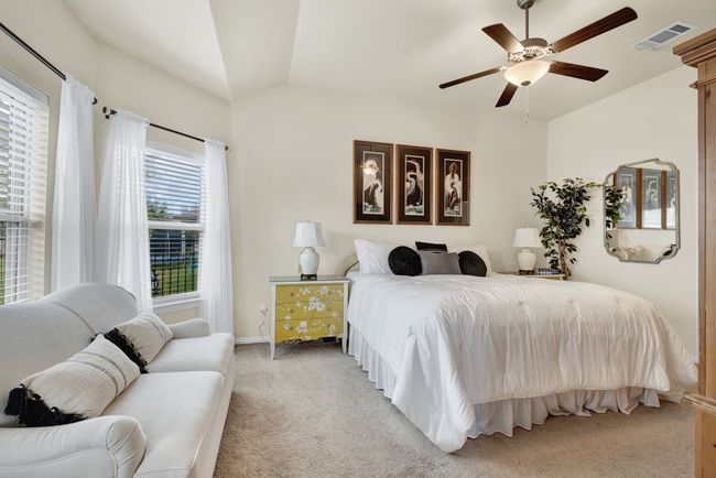 Bedroom featuring ceiling fan, light colored carpet, visible vents, lofted ceiling, and baseboards | Image 15