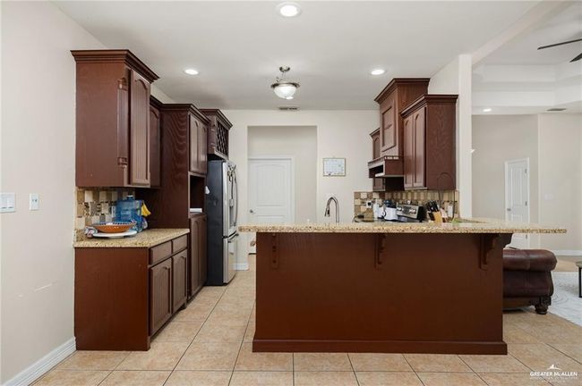Kitchen featuring double oven range, light tile patterned floors, a peninsula, tasteful backsplash, and recessed lighting | Image 7