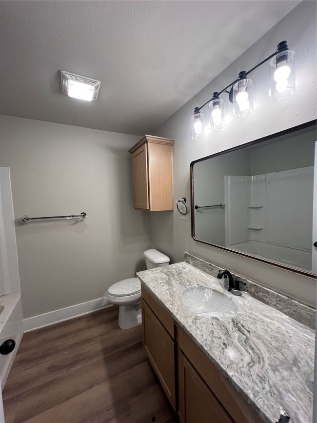 Full bathroom featuring toilet, a washtub, baseboards, wood finished floors, and vanity | Image 11