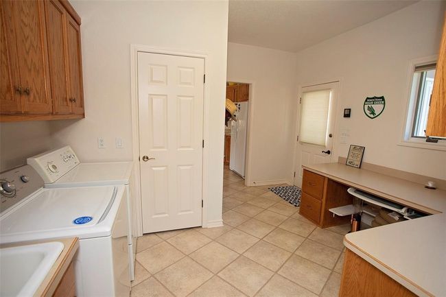 Laundry room with sink, separate washer and dryer, cabinets, and light tile floors | Image 30