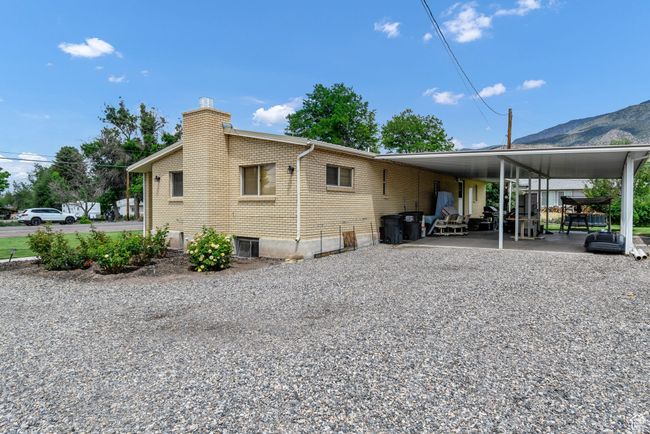 Back of property with a chimney, an attached carport, brick siding, driveway, and a mountain view | Image 4