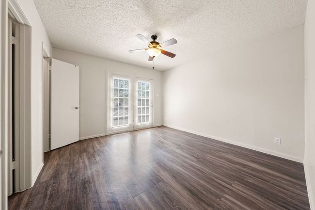 Spare room featuring dark wood finished floors, a textured ceiling, baseboards, and ceiling fan | Image 9