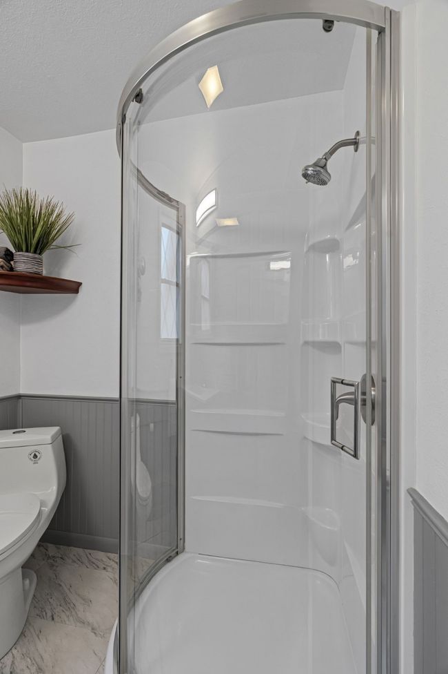 Full bath featuring wainscoting, a shower stall, and marble finish floors | Image 20
