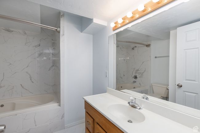 Bathroom with a combined bath / shower with marble appearance, vanity, toilet, marble finish flooring, and baseboards | Image 19