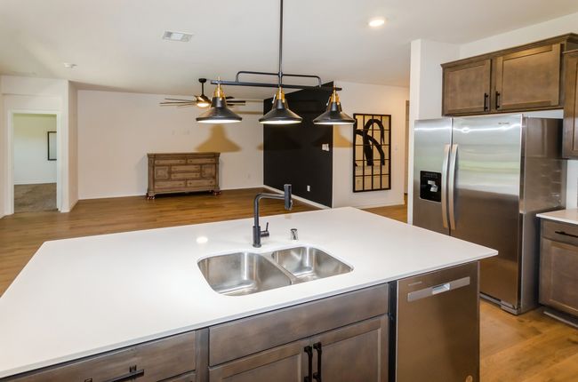 Kitchen featuring appliances with stainless steel finishes, a sink, light wood-style flooring, light countertops, and dark brown cabinets | Image 6