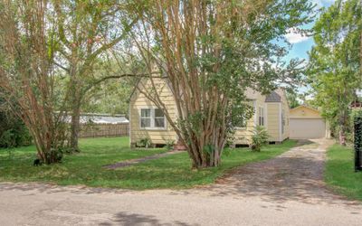 The front yard houses mature trees, a spacious lot, and a private driveway leading to a detached garage. | Image 2