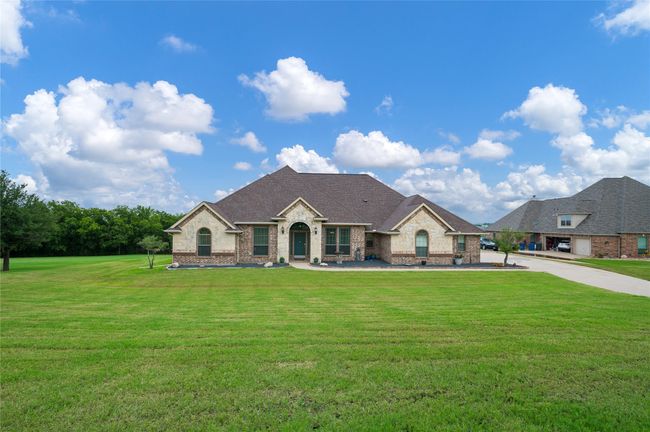 French provincial home featuring brick siding, a front yard, and a shingled roof | Image 21