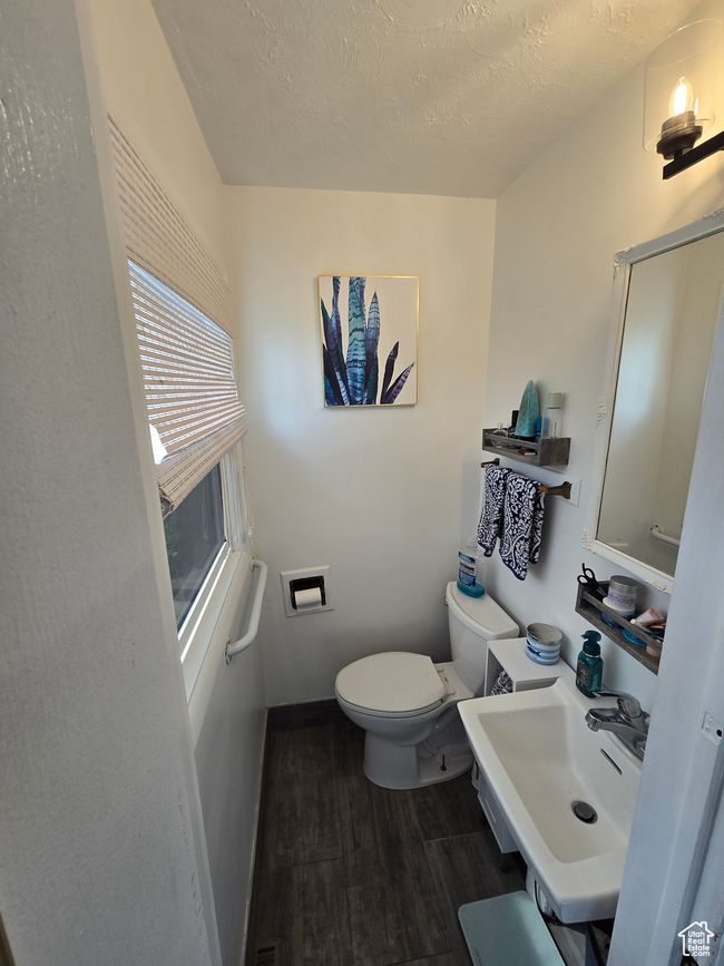 Bathroom featuring a sink, toilet, baseboards, a textured ceiling, and wood finished floors | Image 27