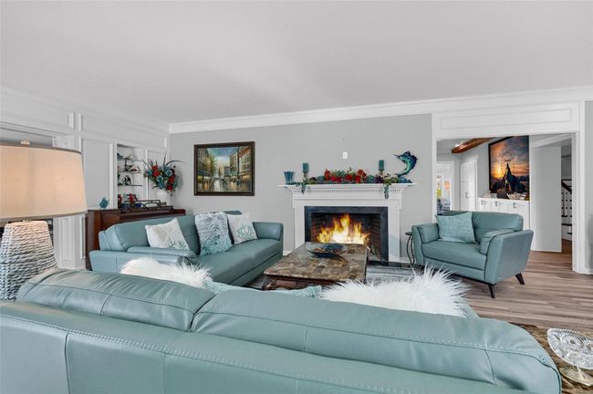 Living area featuring crown molding, wood finished floors, and a warm lit fireplace | Image 9
