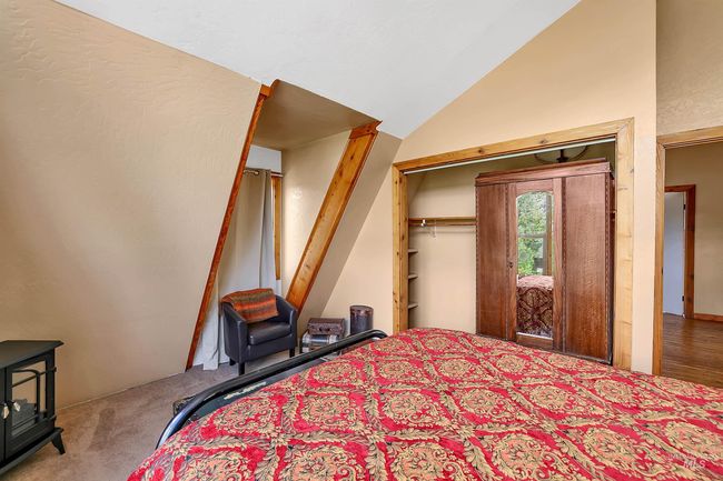 Bedroom with a wood stove, carpet, high vaulted ceiling, and a closet | Image 33