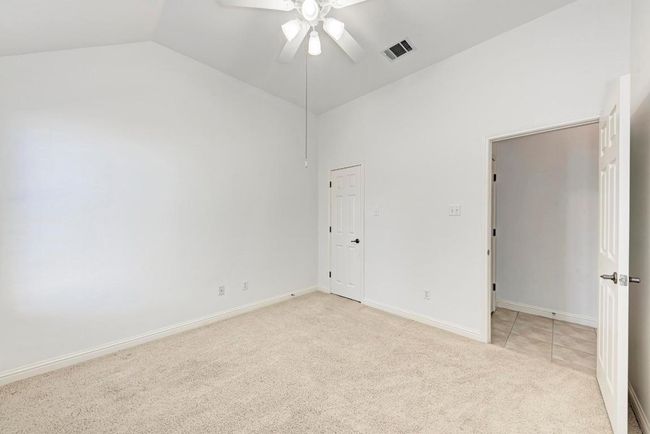 Spare room featuring baseboards, vaulted ceiling, a ceiling fan, visible vents, and light colored carpet | Image 30