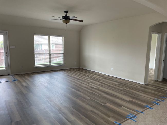 Unfurnished living room with arched walkways, a ceiling fan, plenty of natural light, and dark wood-style flooring | Image 9