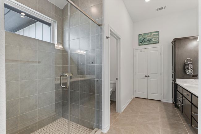 Bathroom featuring a shower stall, tile patterned flooring, visible vents, toilet, and vanity | Image 22
