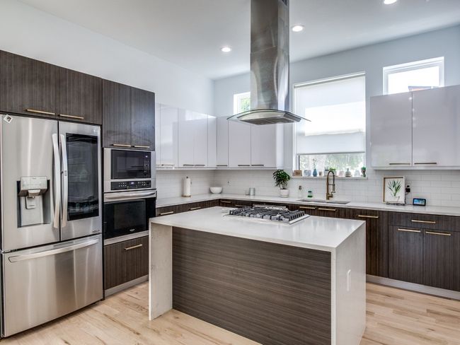 Kitchen with stainless steel appliances, island range hood, dark brown cabinets, decorative backsplash, and recessed lighting | Image 11