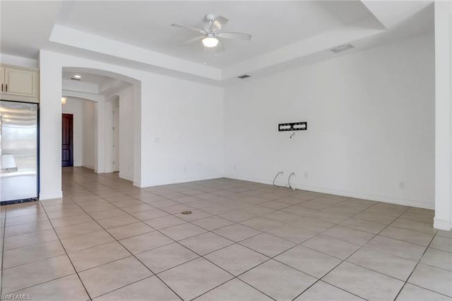 Unfurnished room with a raised ceiling, a ceiling fan, arched walkways, light tile patterned flooring, and baseboards | Image 19