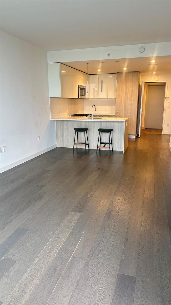 Kitchen featuring modern cabinets, stainless steel microwave, dark wood finished floors, white cabinets, and recessed lighting | Image 7
