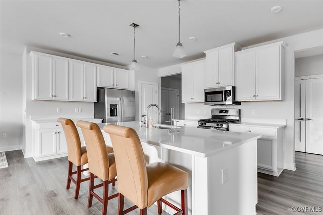 Kitchen with appliances with stainless steel finishes, light countertops, a center island with sink, light wood-style floors, and white cabinets | Image 33