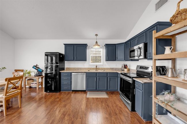 Kitchen featuring wood finished floors, stainless steel appliances, a sink, and vaulted ceiling | Image 13