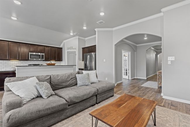 Living area with arched walkways, crown molding, wood like tile flooring, recessed lighting, and vaulted ceiling | Image 25