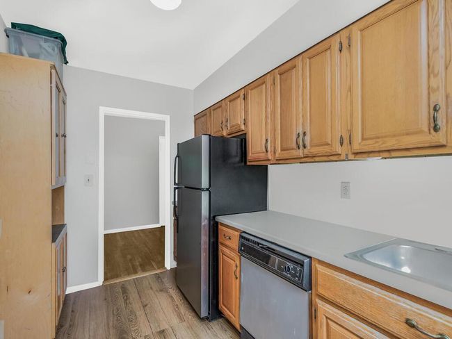 Kitchen featuring white dishwasher, light wood-style floors, light countertops, and freestanding refrigerator | Image 7