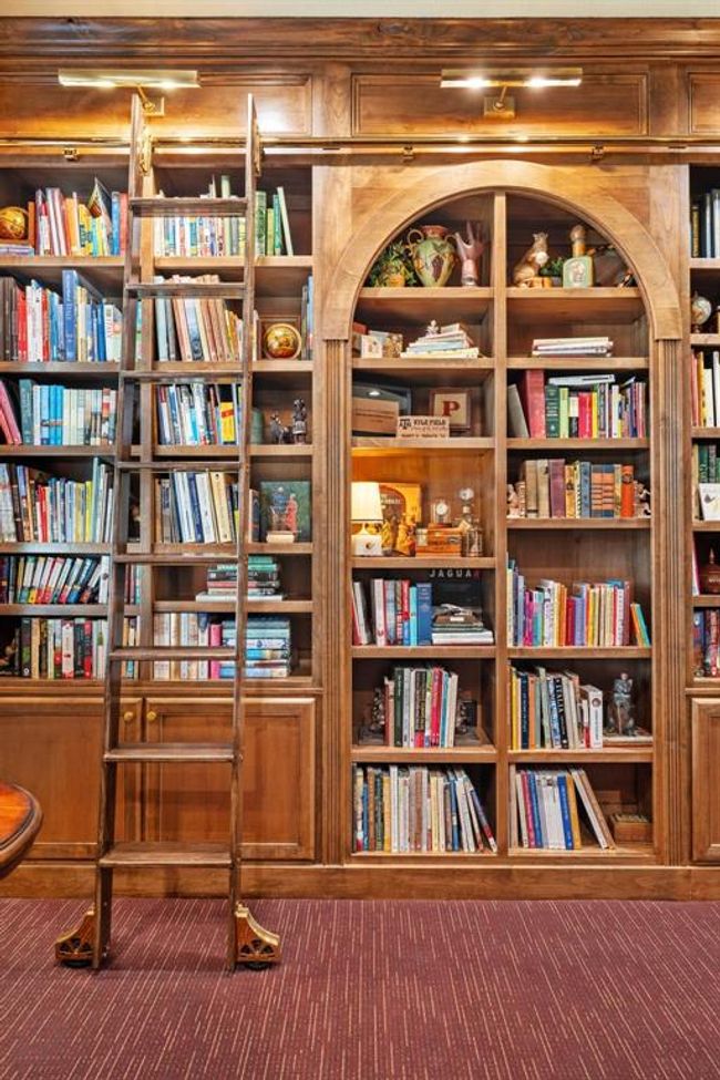 The custom-designed and crafted library wall is complete with an arched center, a rolling library ladder, and lighted glass display case, which is a beautiful feature. | Image 15