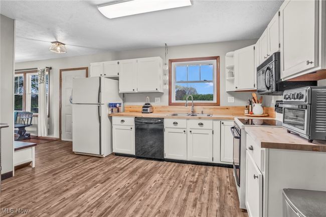 Kitchen featuring wood counters, white cabinets, black appliances, and a sink | Image 16