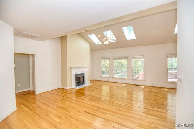 Unfurnished living room featuring a high end fireplace, light wood-type flooring, visible vents, and a wealth of natural light | Image 7
