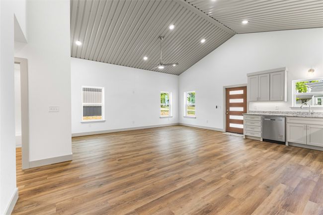 Unfurnished living room featuring high vaulted ceiling, healthy amount of natural light, light wood-type flooring, baseboards, and recessed lighting | Image 12