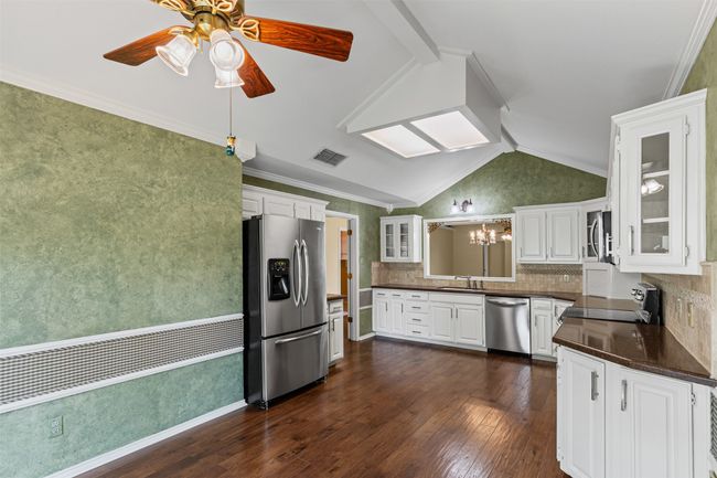 Kitchen featuring appliances with stainless steel finishes, a sink, dark countertops, vaulted ceiling, and dark wood-type flooring | Image 6