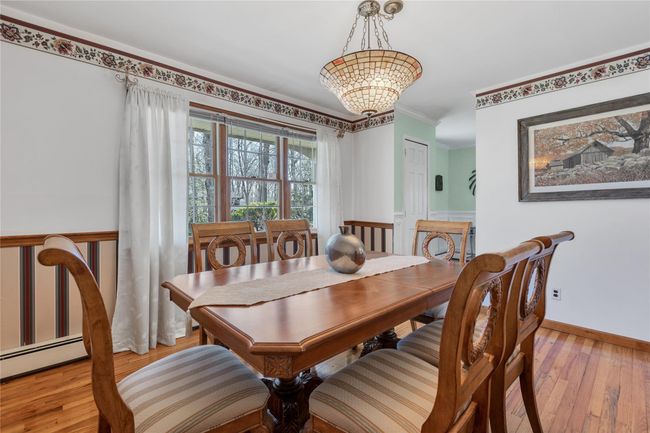 Dining space featuring a baseboard radiator, baseboards, light wood-style floors, ornamental molding, and an inviting chandelier | Image 5