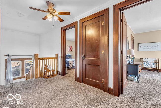 corridor featuring carpet floors, crown molding, and an upstairs landing | Image 29