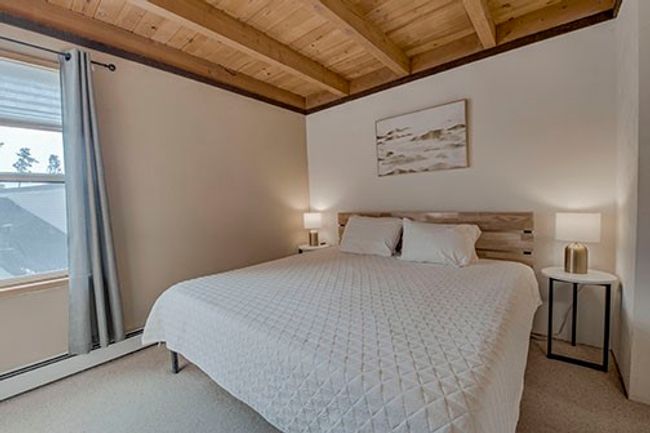 King bed, carpeted bedroom featuring wood ceiling, beamed ceiling, and baseboard heating | Image 12
