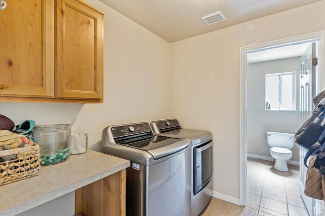Laundry area featuring independent washer and dryer, cabinet space, baseboards, and light tile patterned flooring | Image 11
