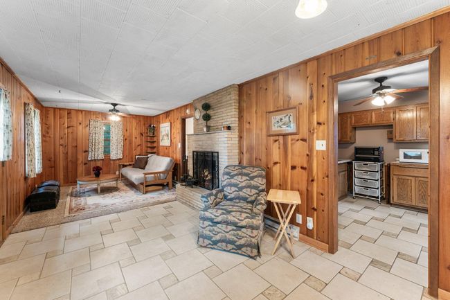Step into a bright dining area with built-in china cabinets, tile flooring, and wood-paneled walls. | Image 19