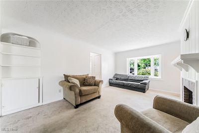 Carpeted living room with a fireplace and a textured ceiling | Image 2