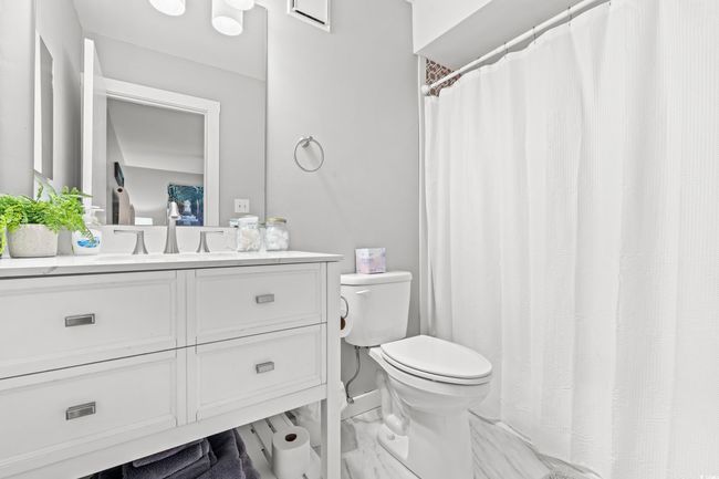 Bathroom with toilet, vanity, marble finish floors, and a shower with curtain | Image 16