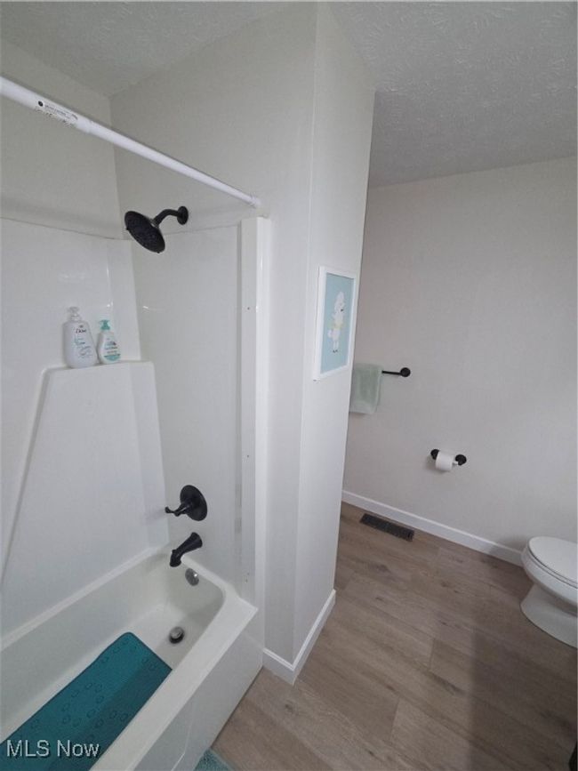 Bathroom with visible vents, toilet, a textured ceiling, wood finished floors, and shower / tub combination | Image 25