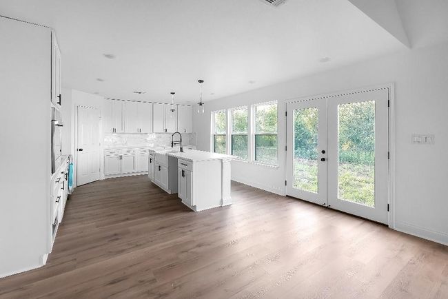 Kitchen featuring a sink, light countertops, dark wood finished floors, white cabinetry, and backsplash | Image 5