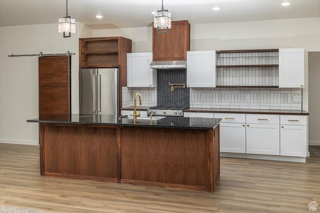 Kitchen with pendant lighting, premium appliances, white cabinetry, and a kitchen island with sink | Image 8