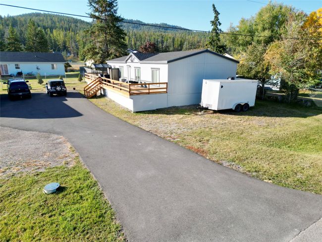 View of front of property with a wooden deck, a front yard, and a forest view | Image 28