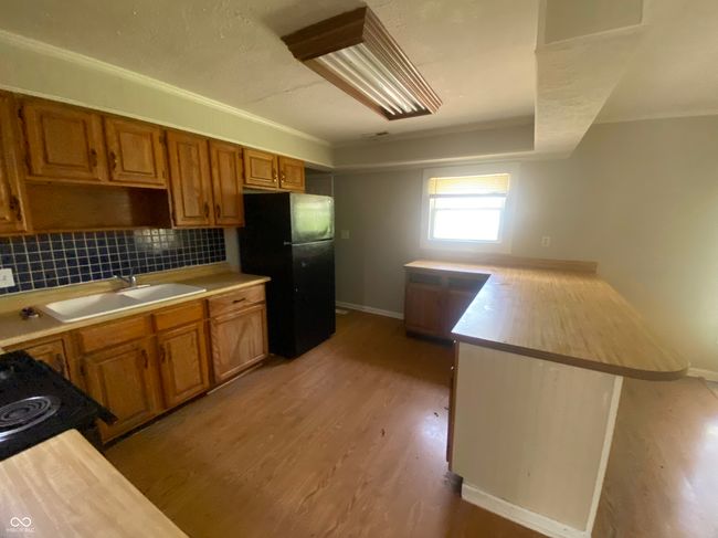kitchen with a sink, light wood-style floors, light countertops, black appliances, and a peninsula | Image 5
